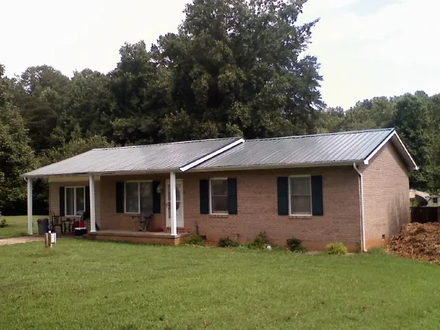 Gray metal roof on a brick ranch house with a side carport in Granville