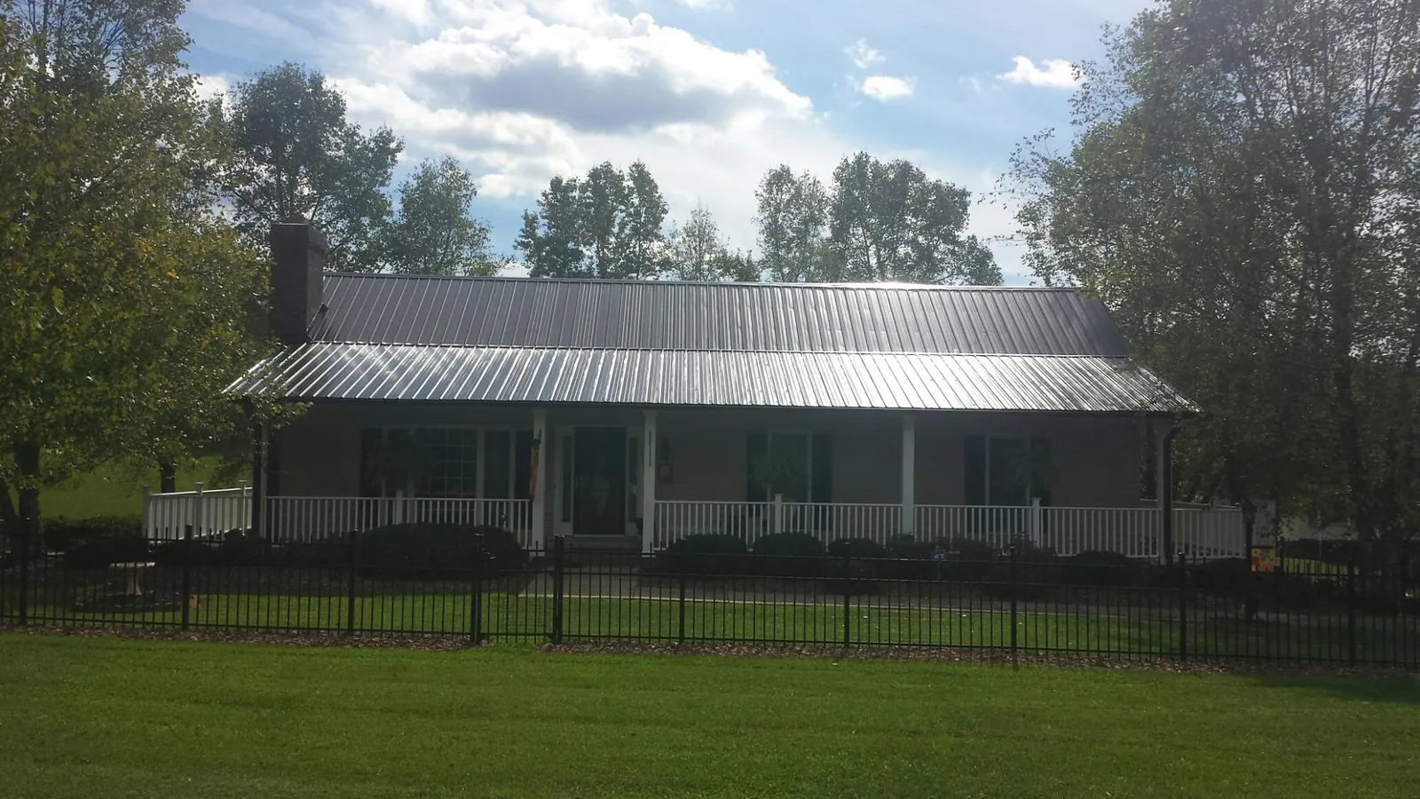 Gray metal roof on a brick ranch with a full width front porch — Gutter Guard Installation work by our crew in Granville